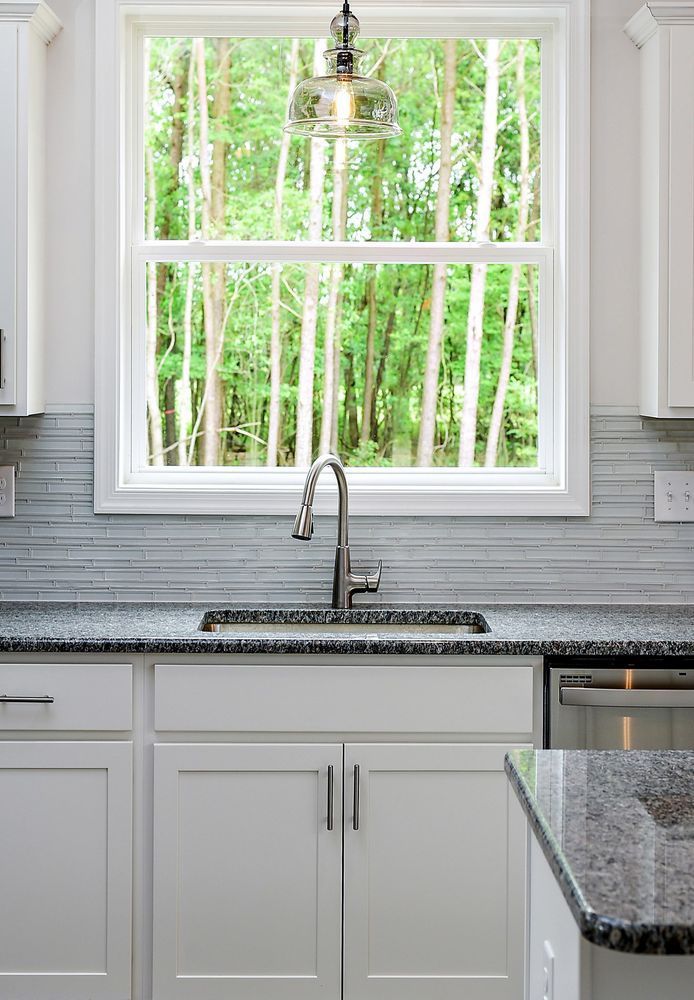 A kitchen with a sink and a window with trees in the background.