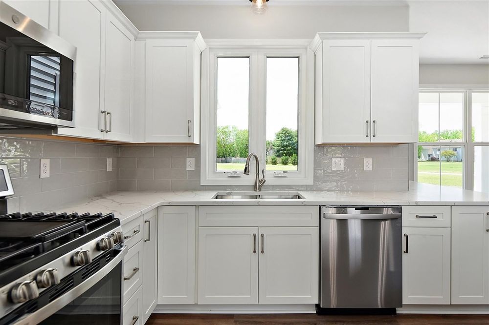 A kitchen with white cabinets, stainless steel appliances, a stove, and a sink.