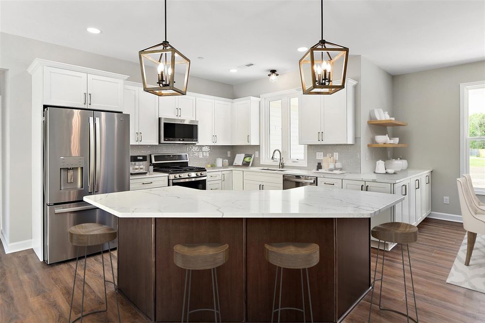 A kitchen with white cabinets, stainless steel appliances, and a large island.
