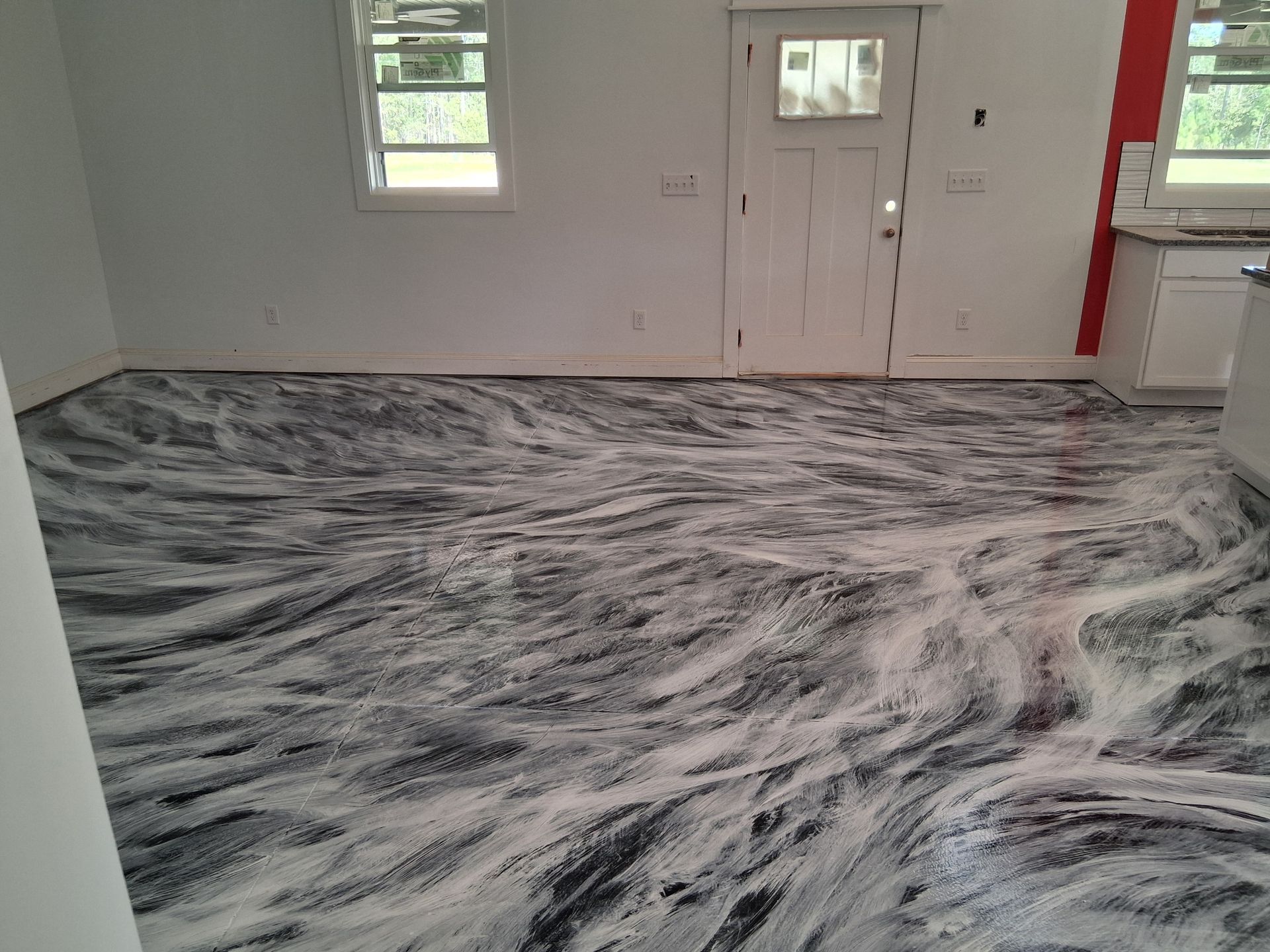 A room with freshly applied, marbled epoxy flooring featuring swirled black and white patterns against white walls.