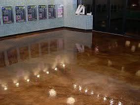 A highly reflective brown floor with marble-like patterns in a room with illuminated display cases along a light blue wall.