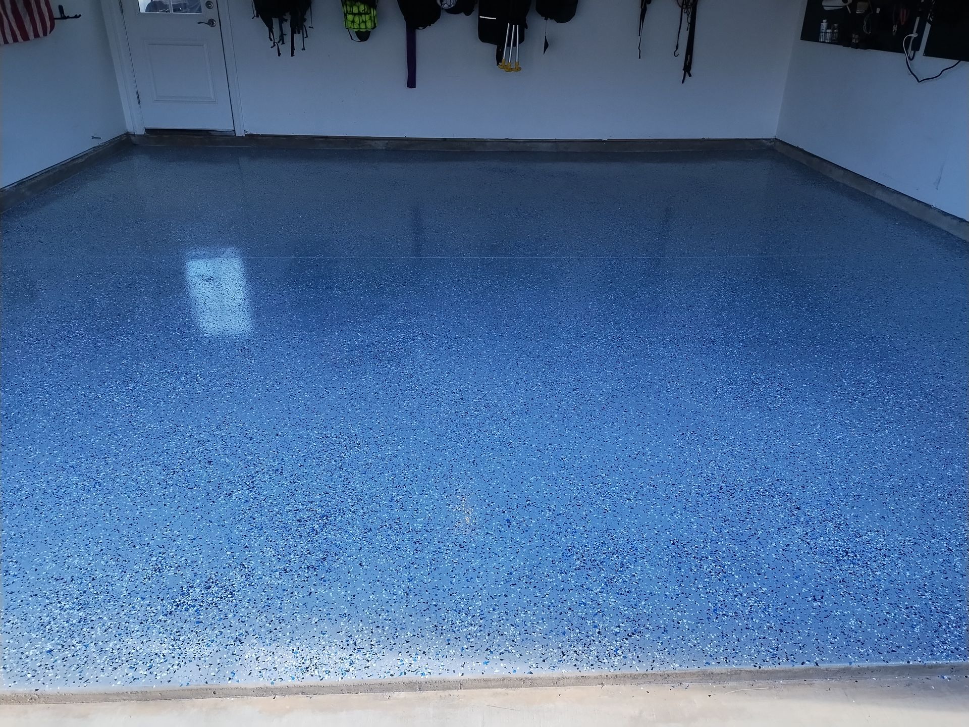 A freshly coated garage floor with a blue and grey speckled epoxy finish.