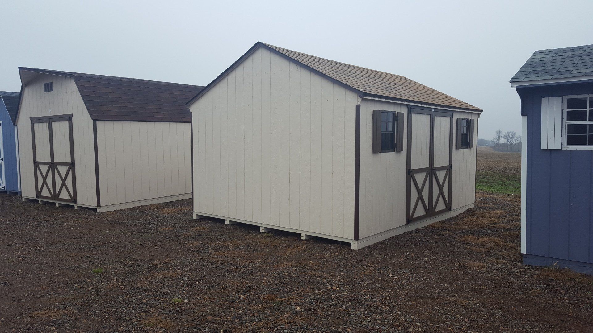 A group of sheds are lined up in a field.