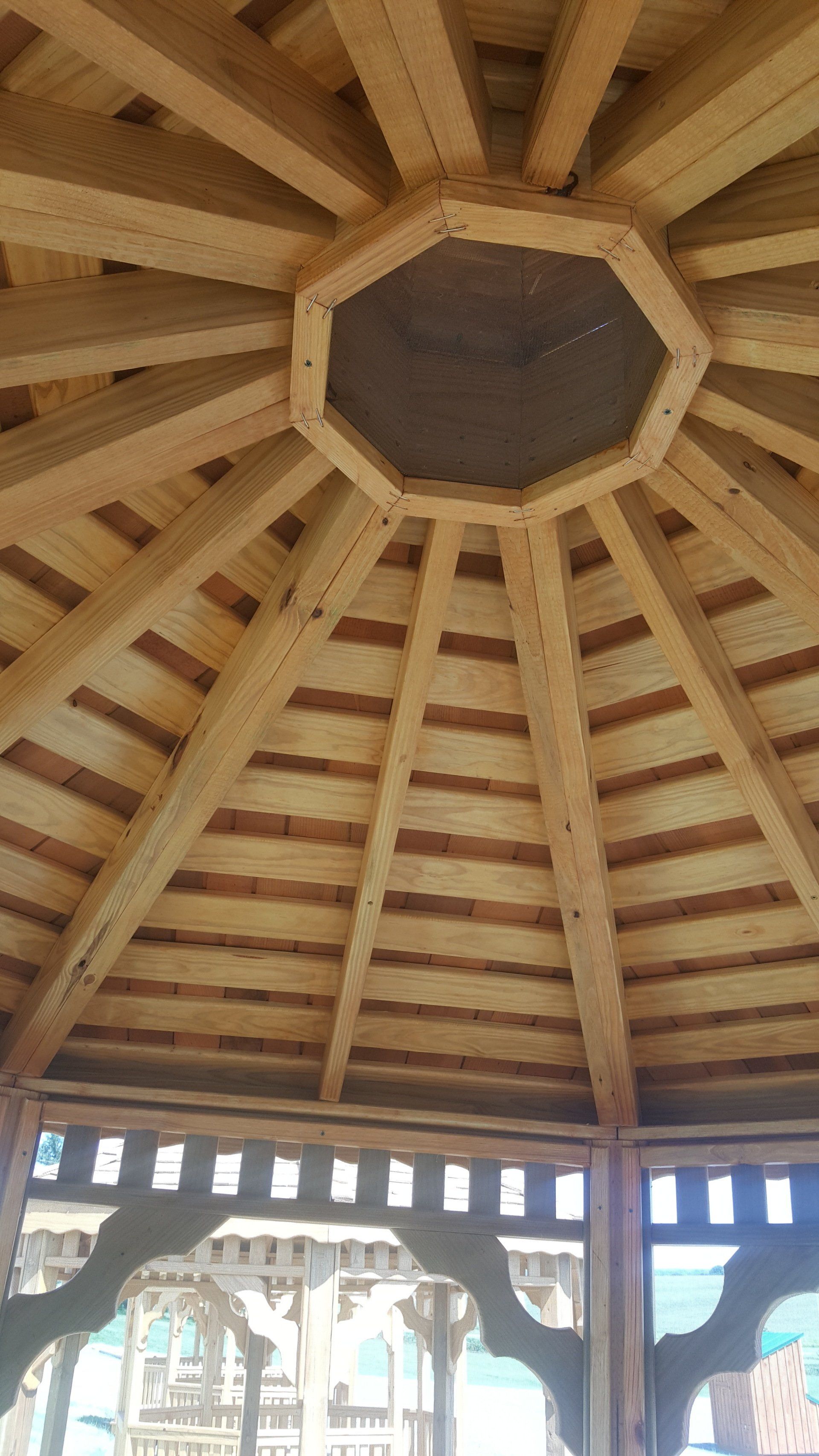 The inside of a wooden gazebo with a wooden ceiling.