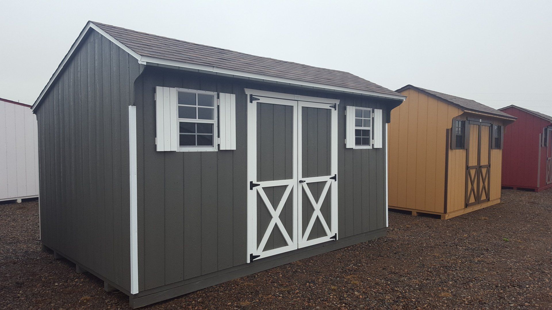 A row of sheds are lined up in a gravel yard.