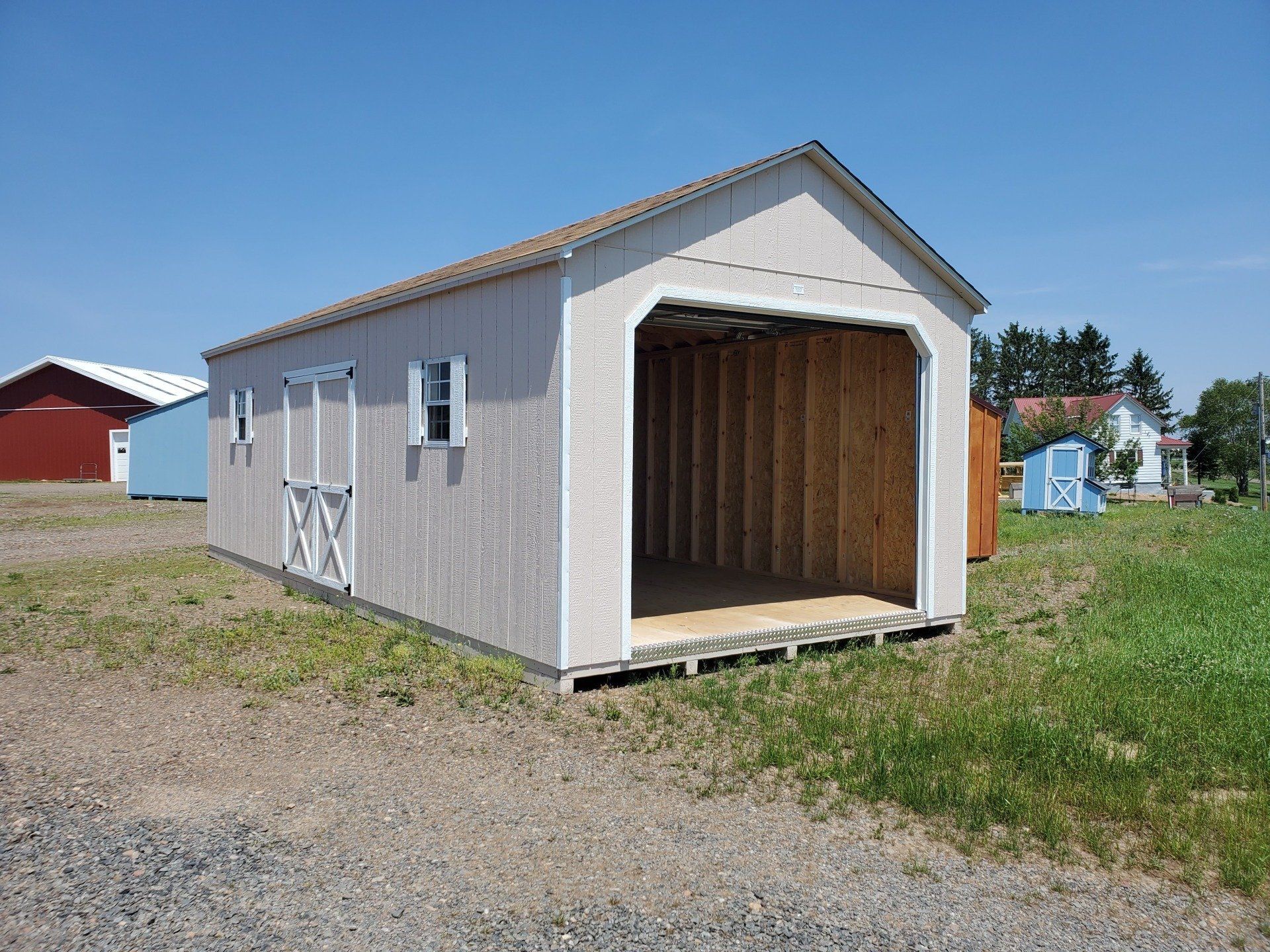 A small garage is sitting in the middle of a grassy field.