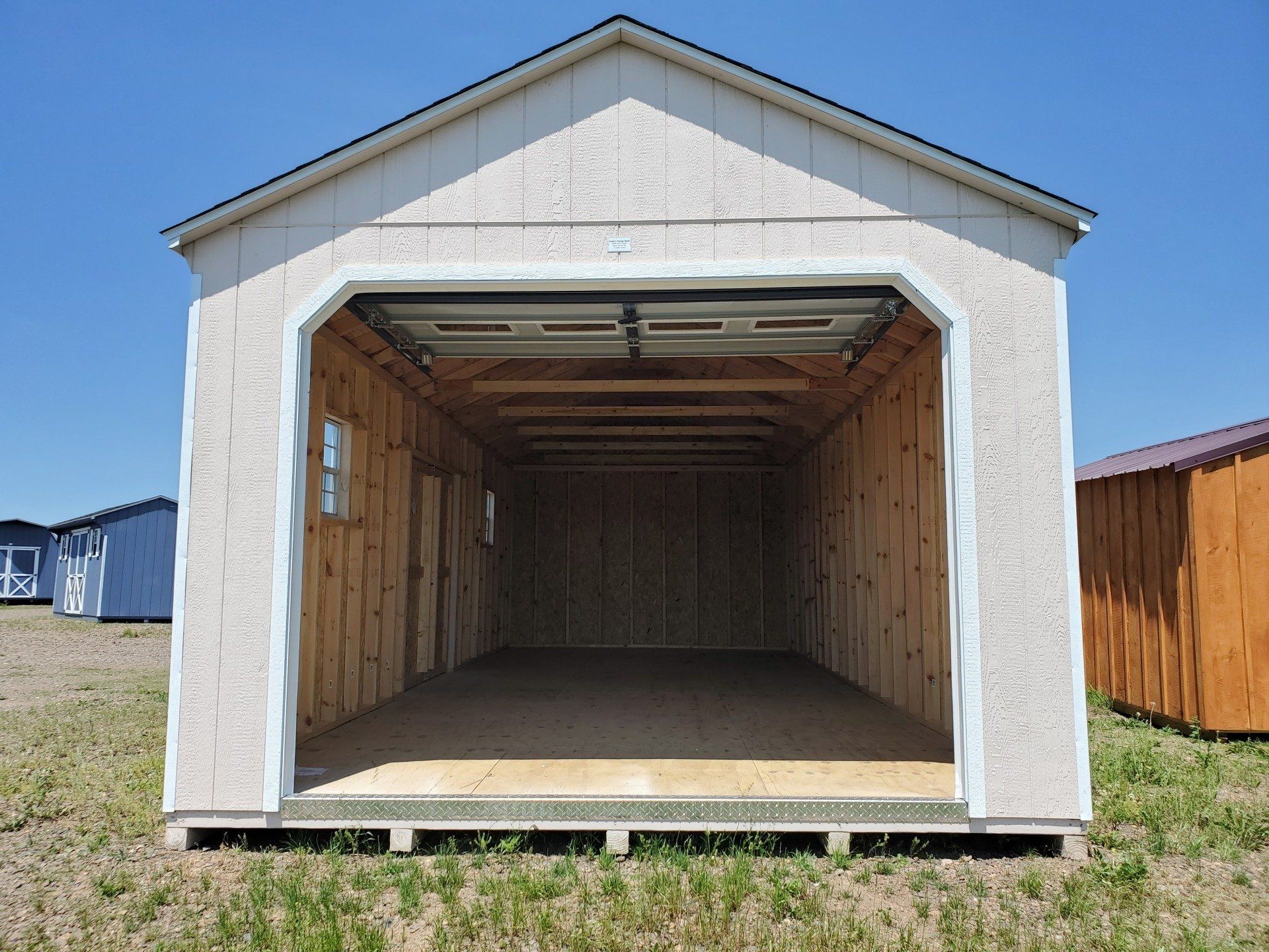 An empty garage with a garage door open in a field.