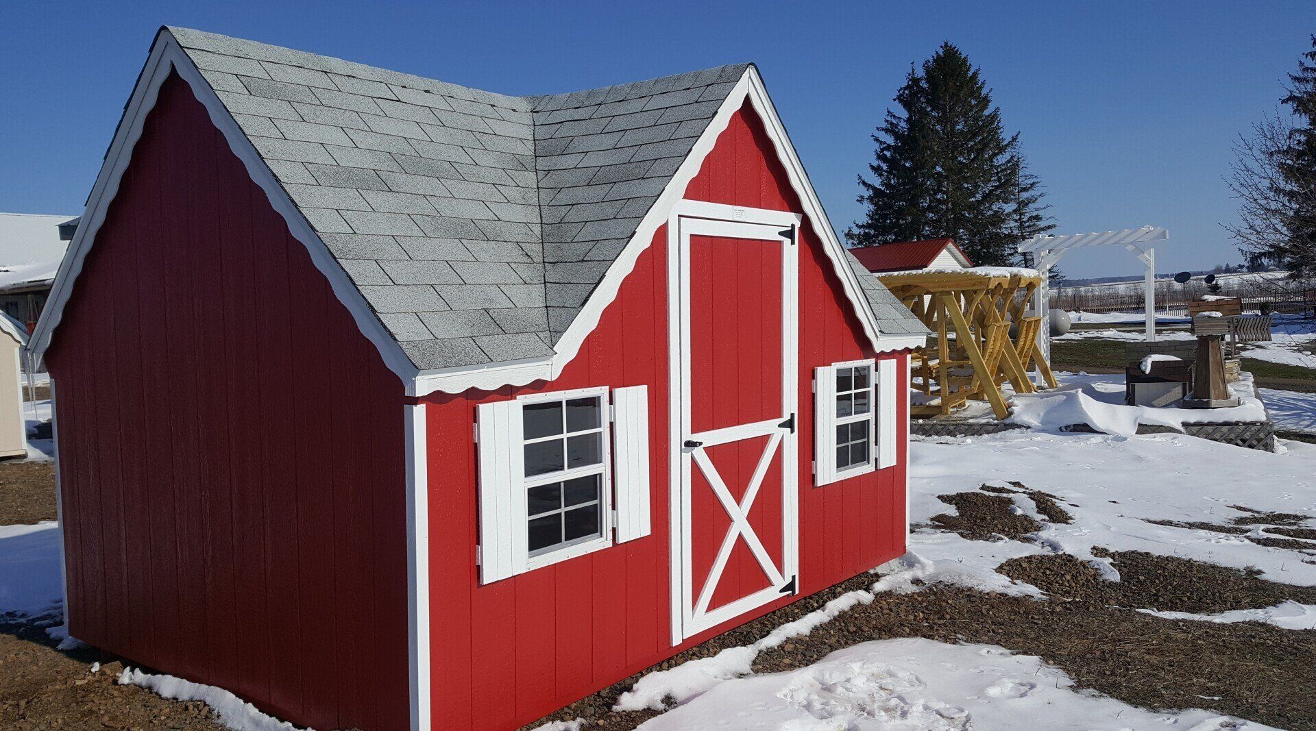 A red barn with white shutters is in the snow