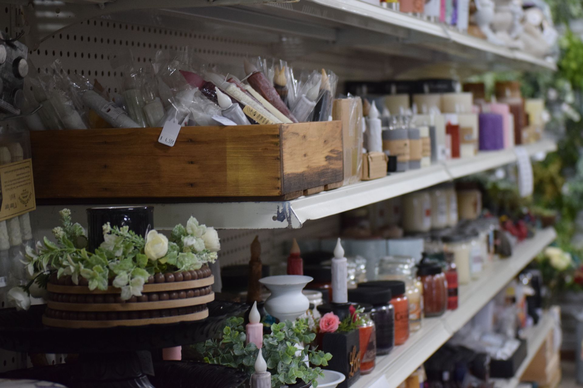 A store shelf filled with lots of candles and flowers.
