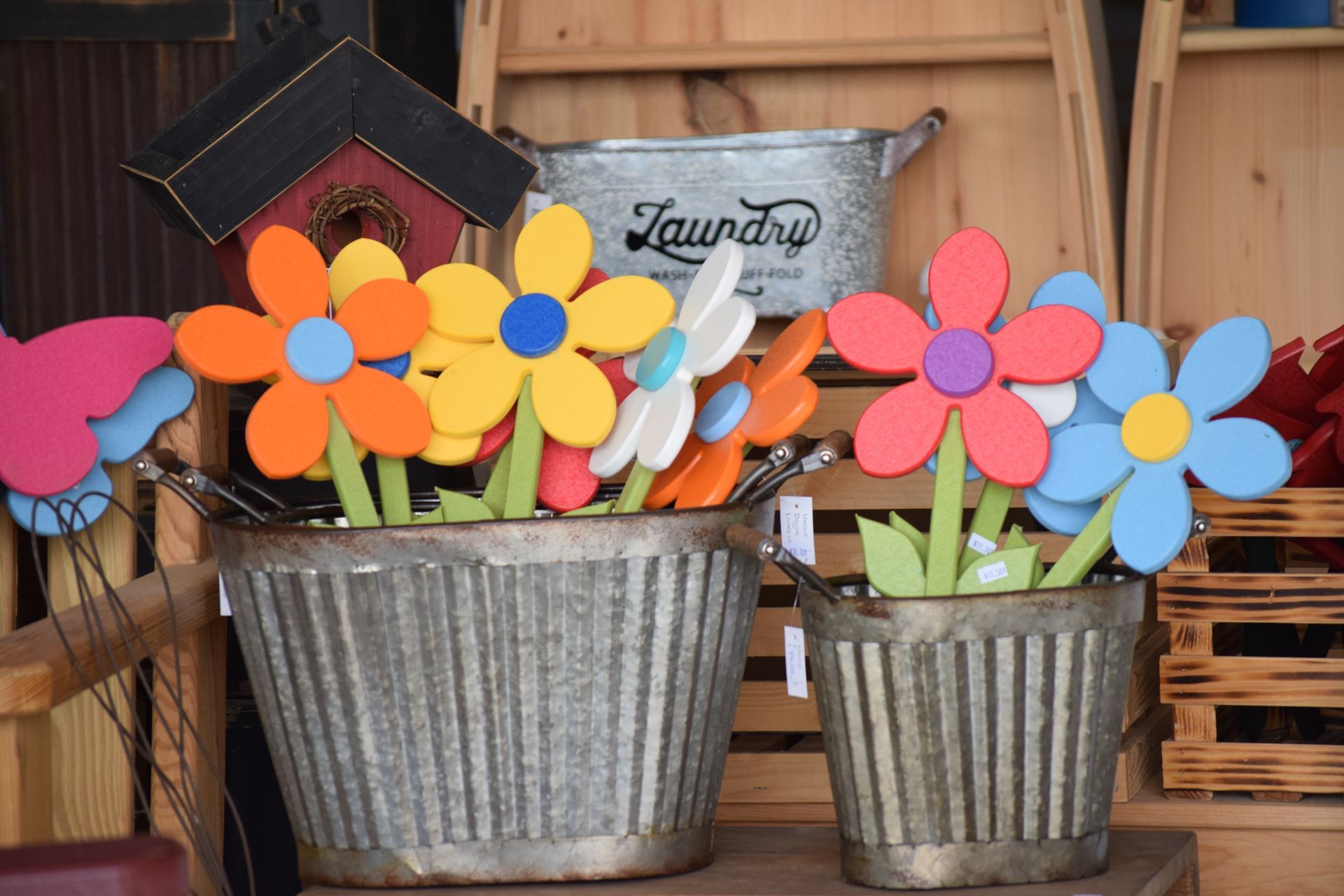 Two metal buckets filled with wooden flowers and a laundry bucket in the background