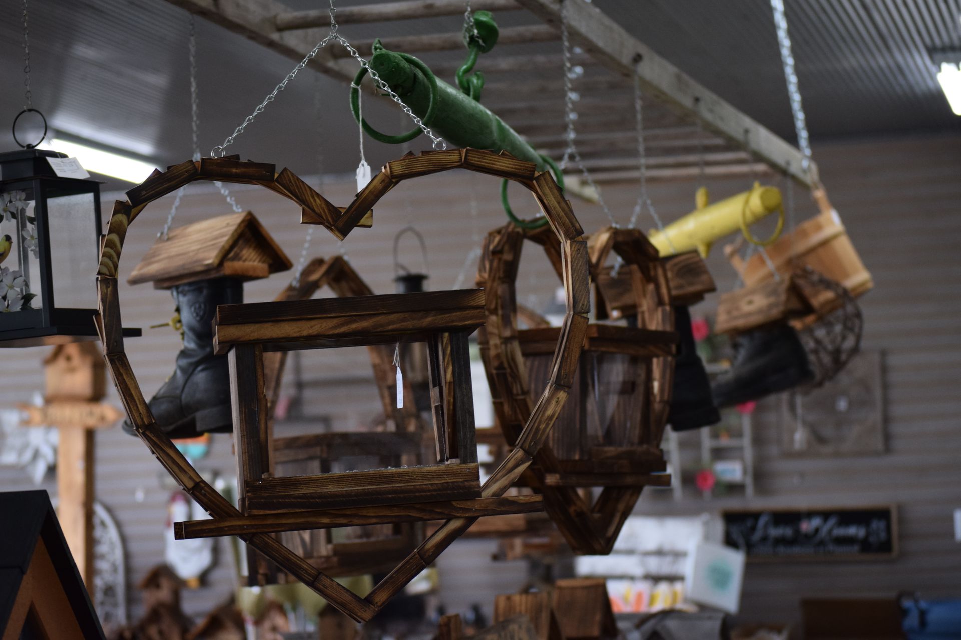 A heart shaped bird feeder is hanging from the ceiling in a store.