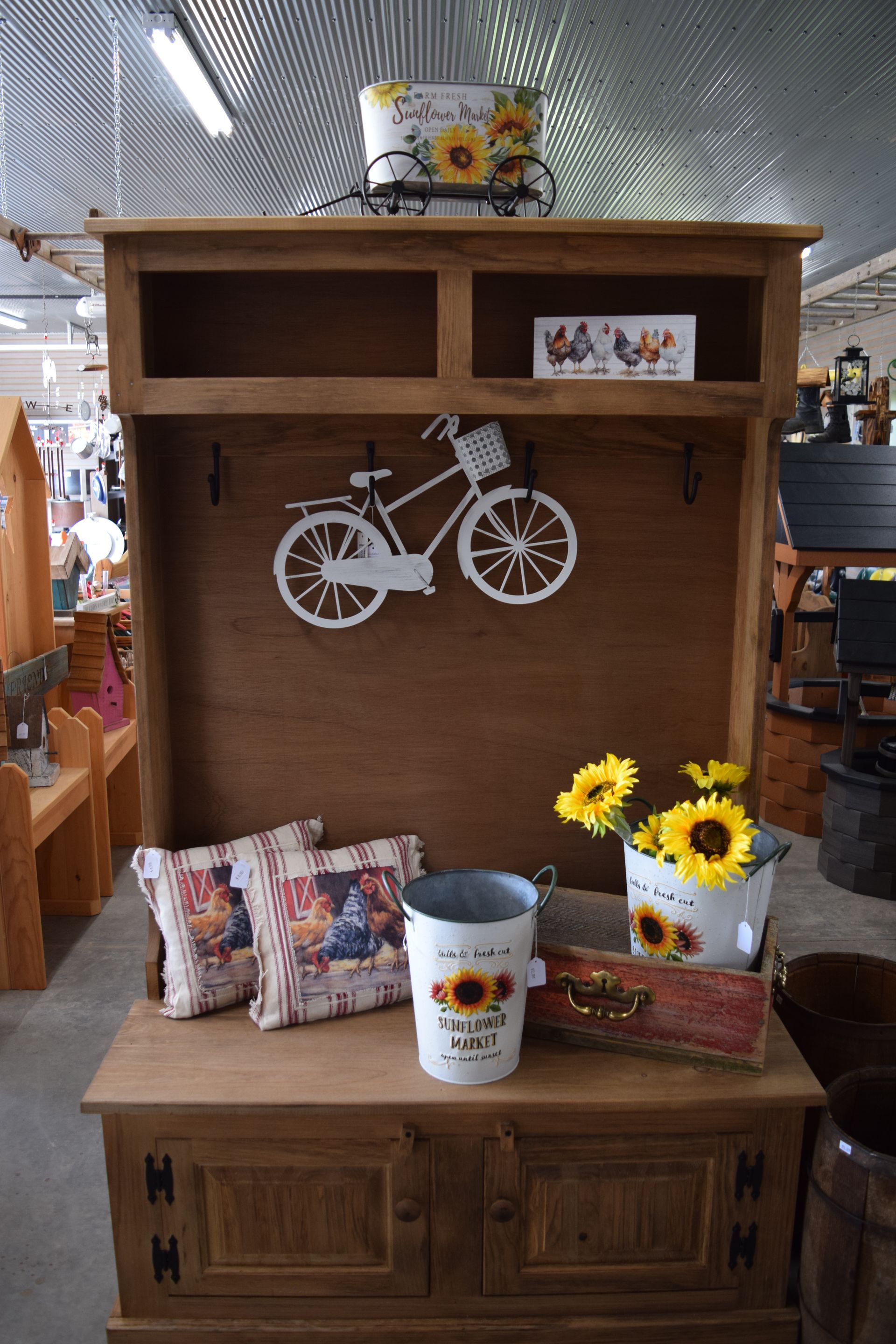A wooden shelf with a bicycle hanging on it and sunflowers in pots.