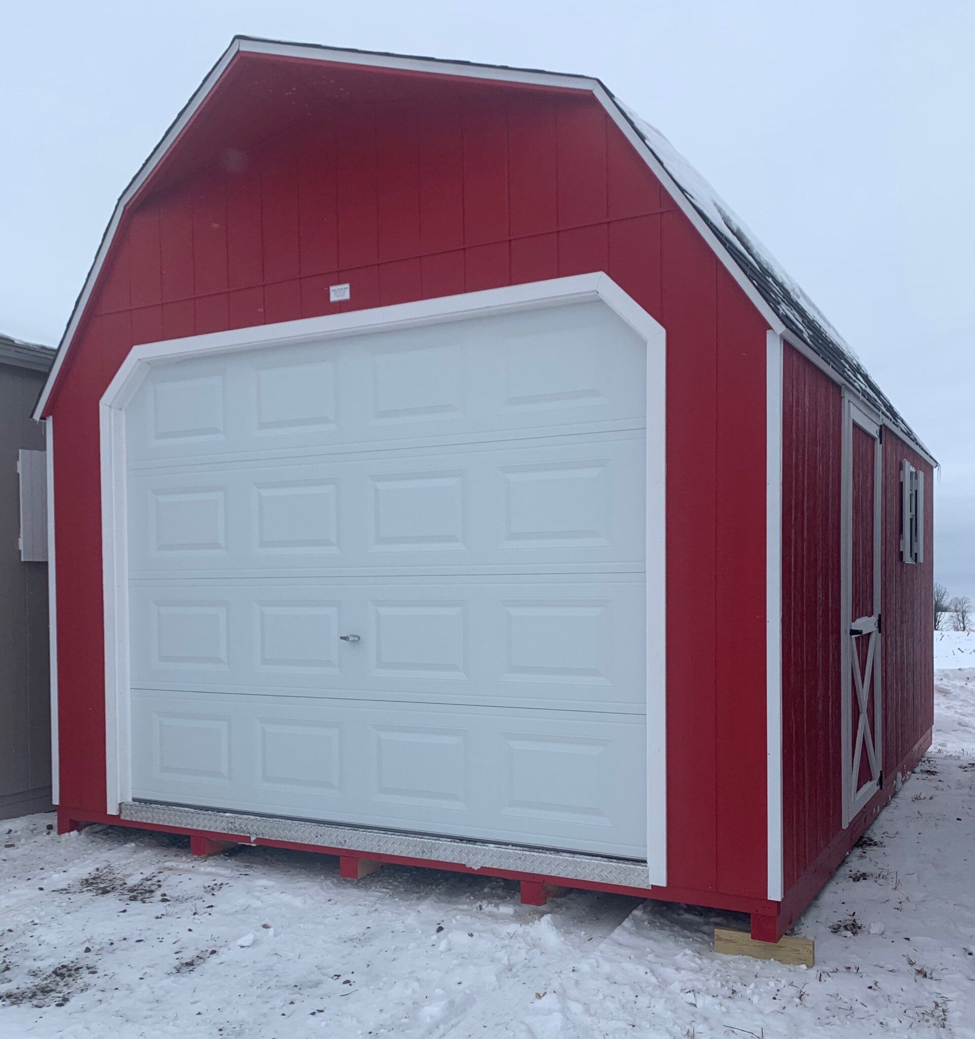 A red barn with a white garage door in the snow