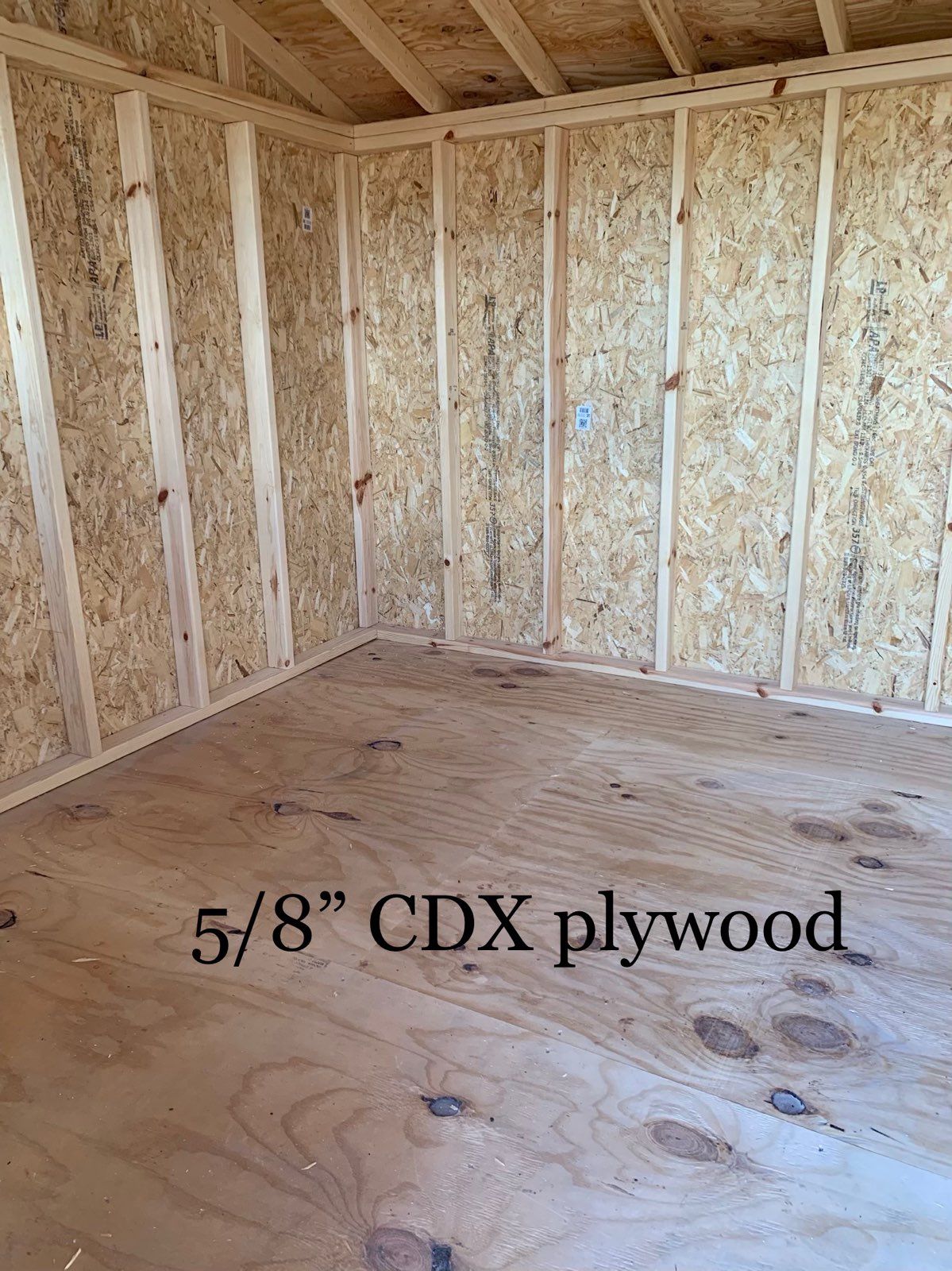 A room with a wooden floor and walls made of cdx plywood.
