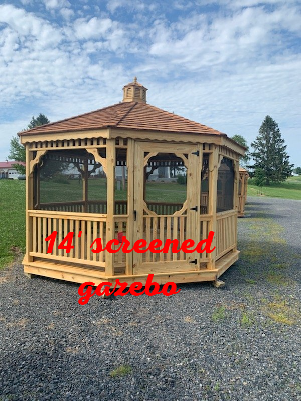 A screened gazebo is sitting in the middle of a gravel road