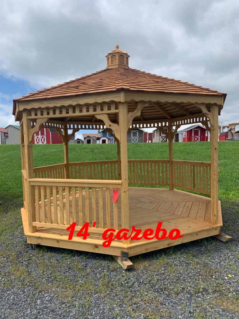 A wooden gazebo is sitting in the middle of a grassy field.