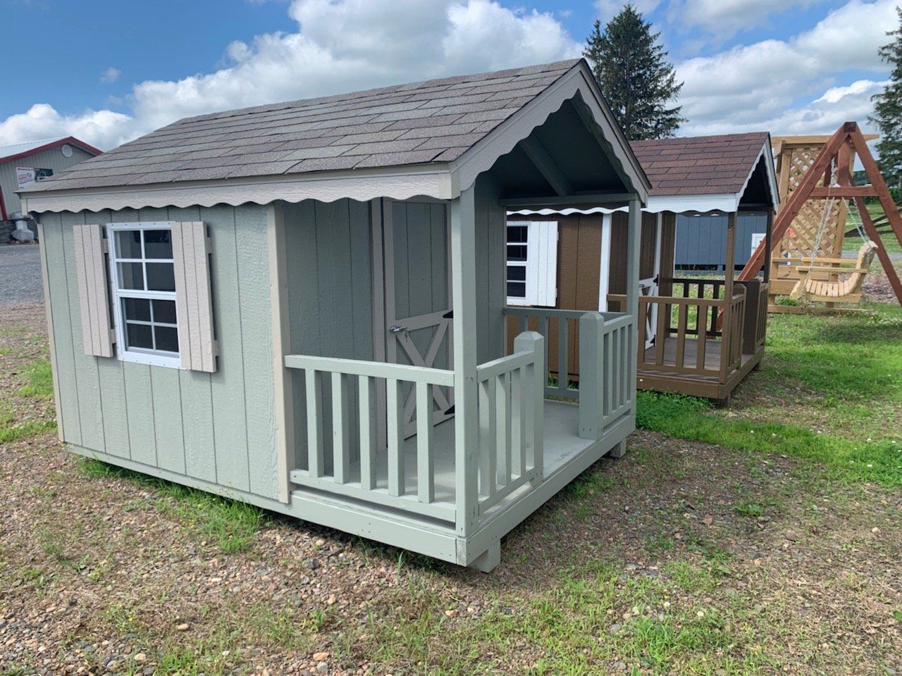 A small playhouse with a porch is sitting in the grass.