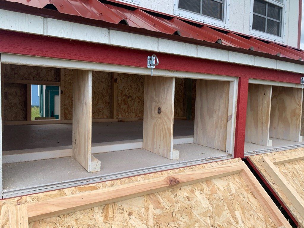 A chicken coop is being built with wooden walls and a red roof.