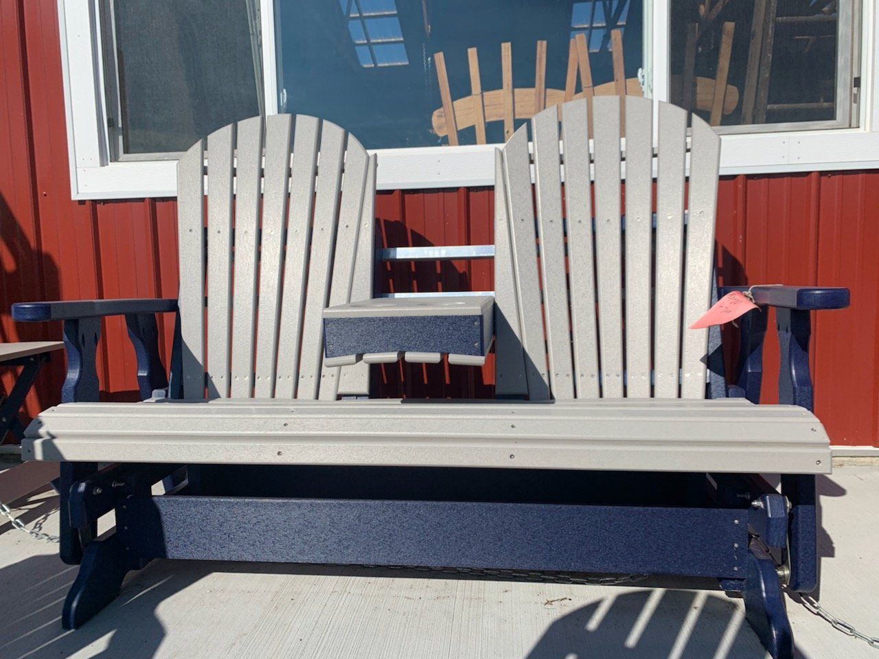 A blue and white adirondack chair is sitting in front of a red building