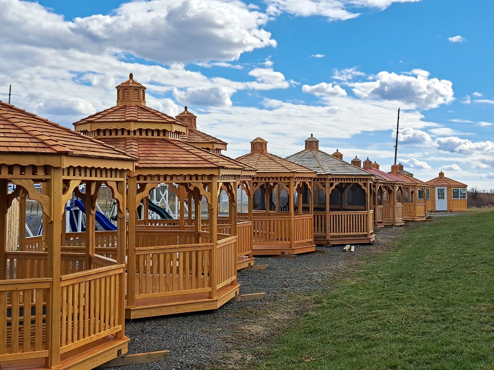 A row of wooden gazebos are lined up in a field.