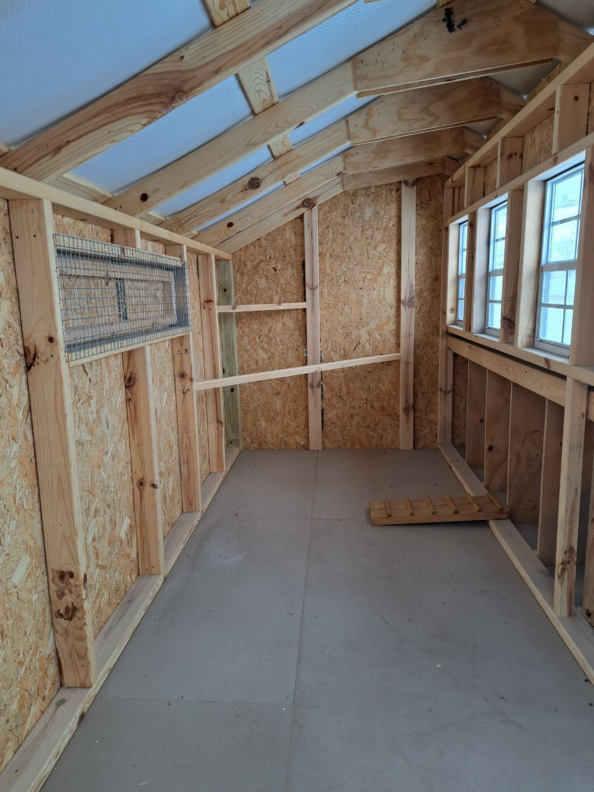 A wooden shed is being built with a lot of windows.