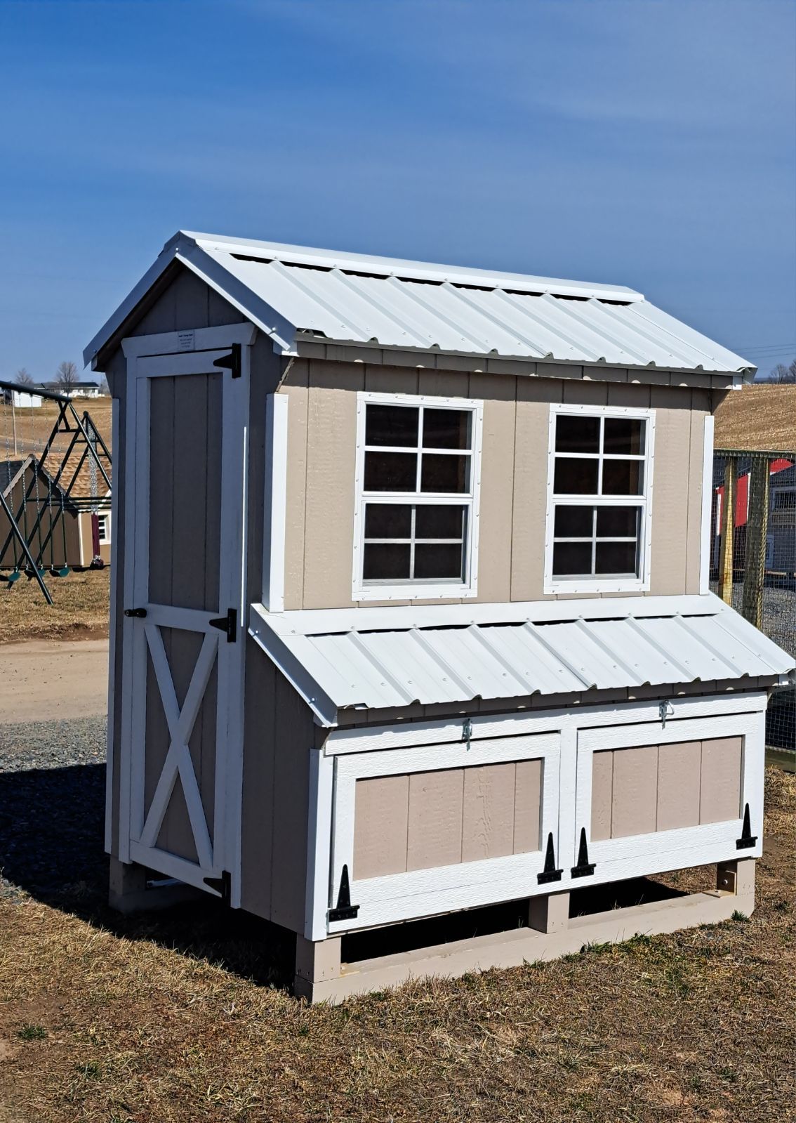 A small chicken coop with a white roof is sitting in the grass.