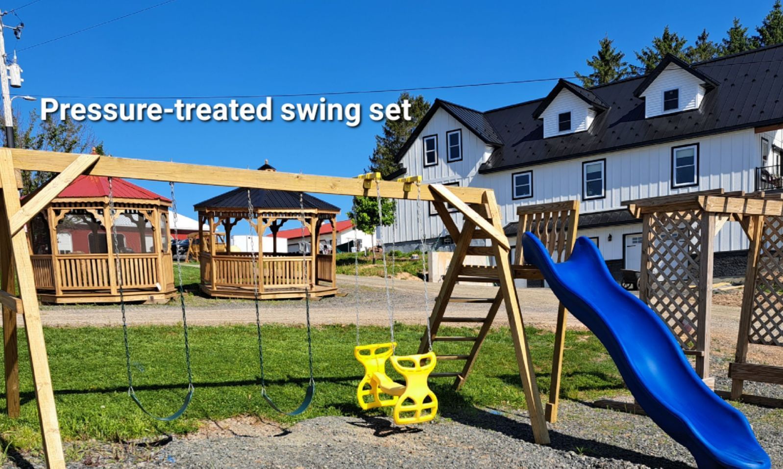 A pressure treated swing set with a blue slide and swings