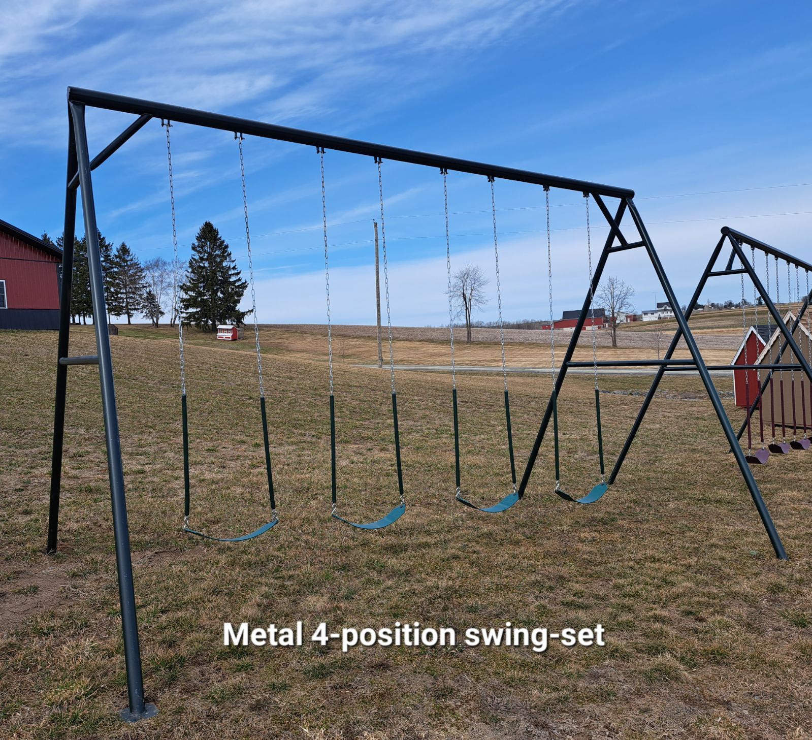 A metal 4 position swing set in a grassy field