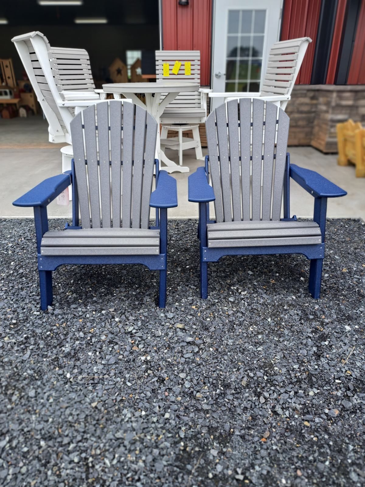 Two adirondack chairs are sitting on gravel in front of a building