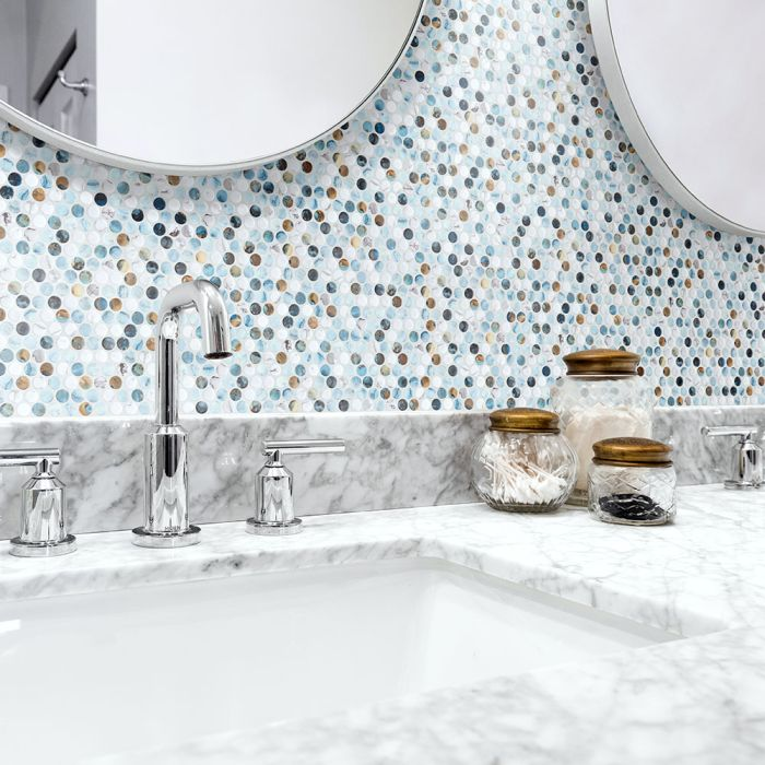 Bathroom vanity with marble countertop, mosaic tile backsplash, two mirrors, and jars.