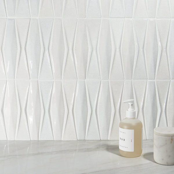 White, diamond-patterned tile wall with a soap dispenser and small marble jar.
