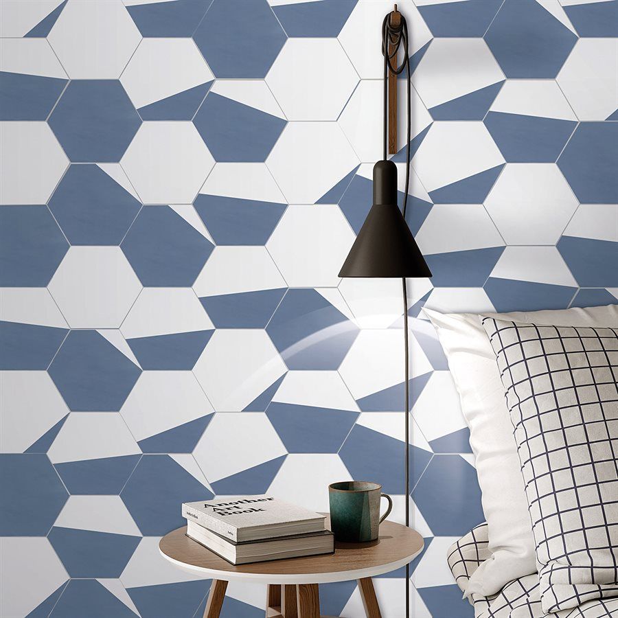 Bedroom with blue and white geometric tile wall, side table, lamp, and bedding.