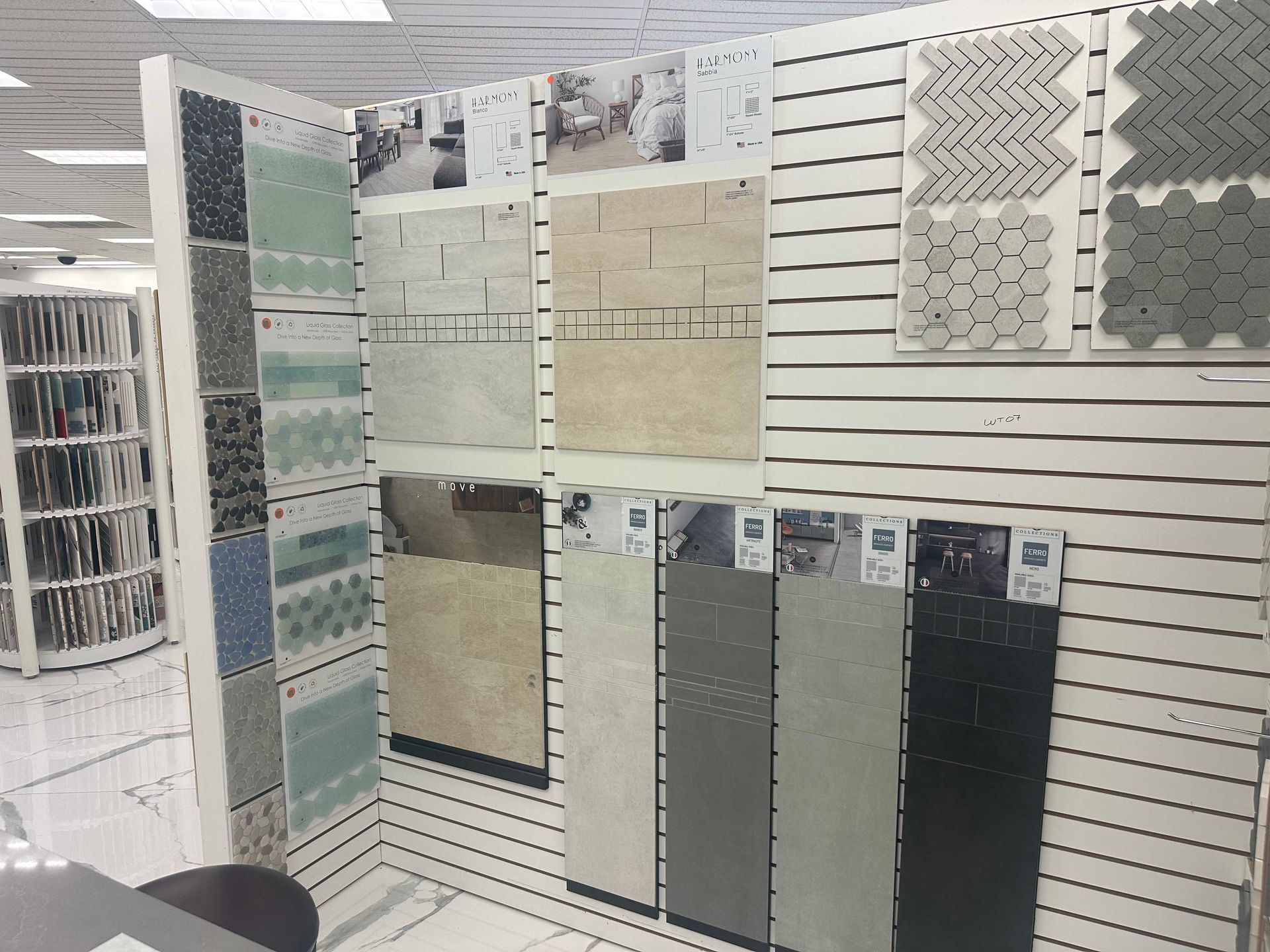 Display of various tile samples on a slotted wall, showcasing different colors and patterns in a showroom.