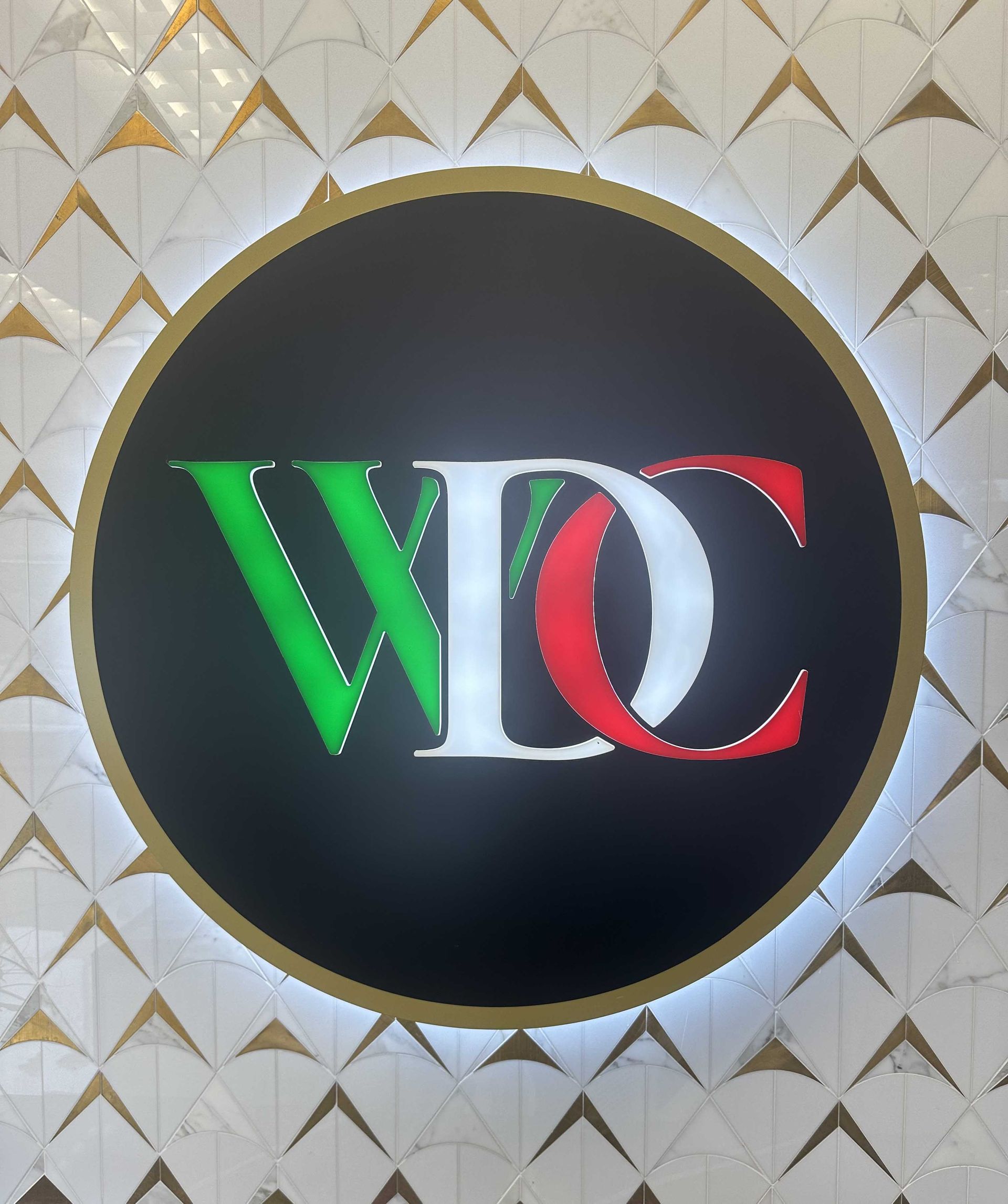 Circular sign with black background, gold trim, and initials WDC in green, white, and red.