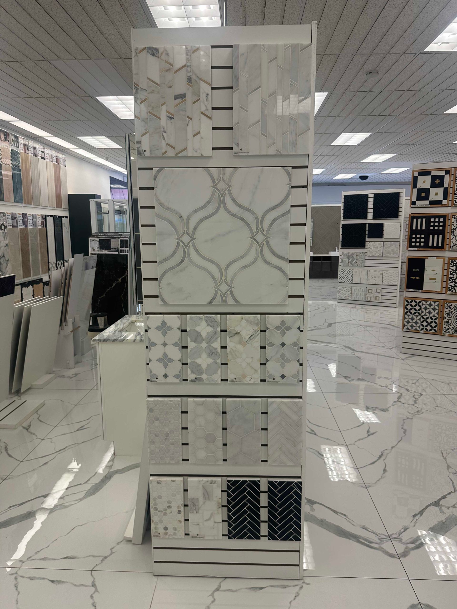 Tile display stand showcasing various marble tile samples in a showroom.