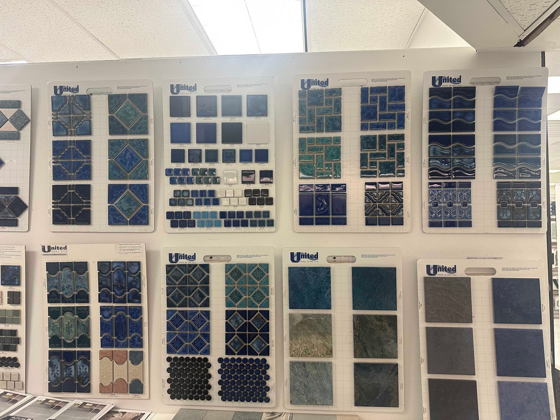 Tile samples on display, various shades of blue and patterns, in a store setting.