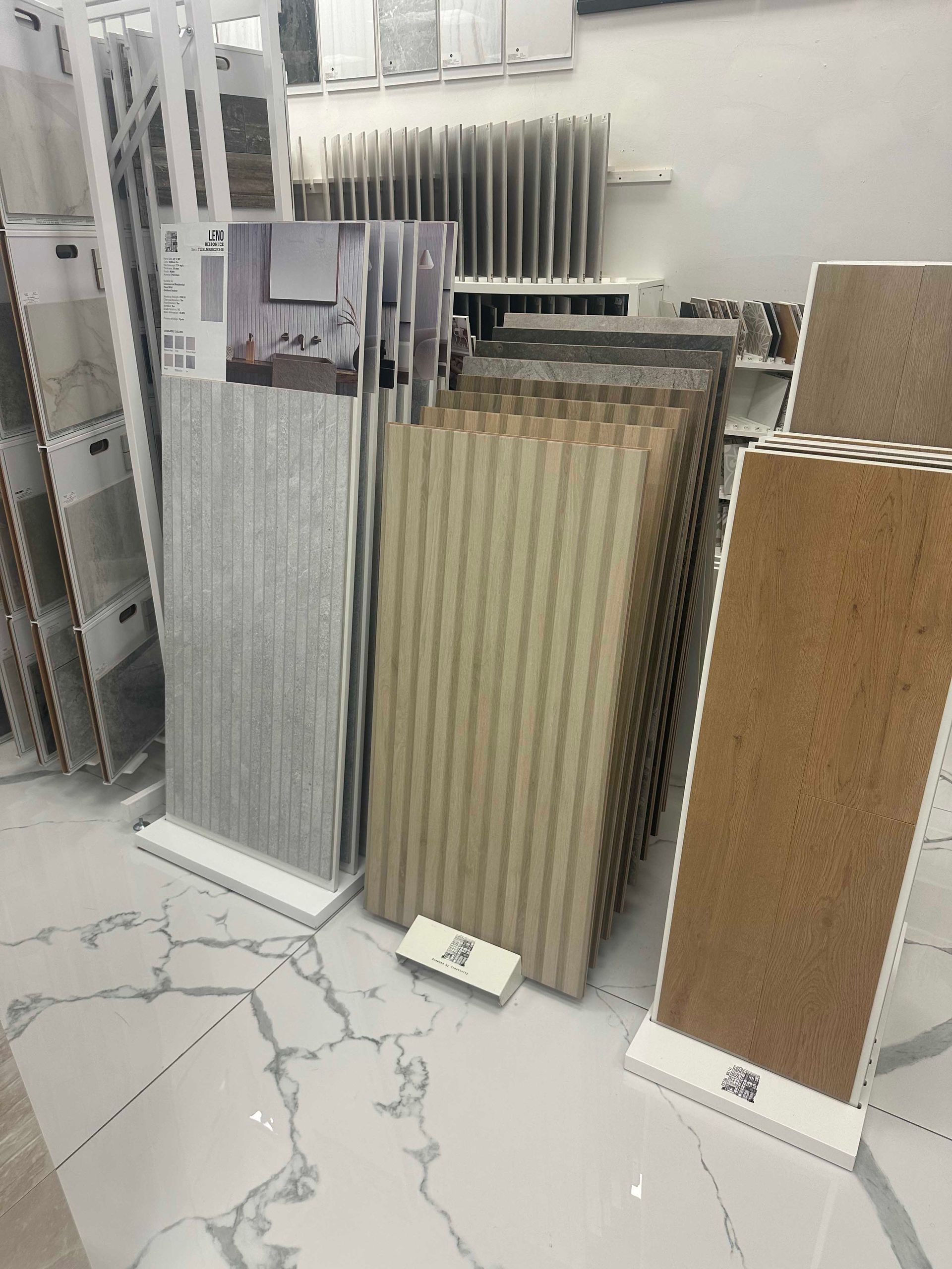 Tile samples in a showroom, arranged on display stands, various colors and textures.
