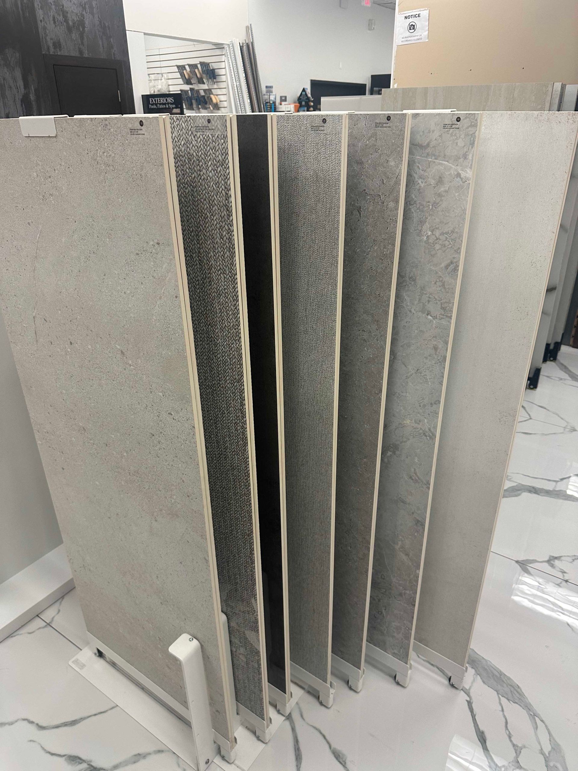 Samples of gray and white tiles displayed upright in a showroom.