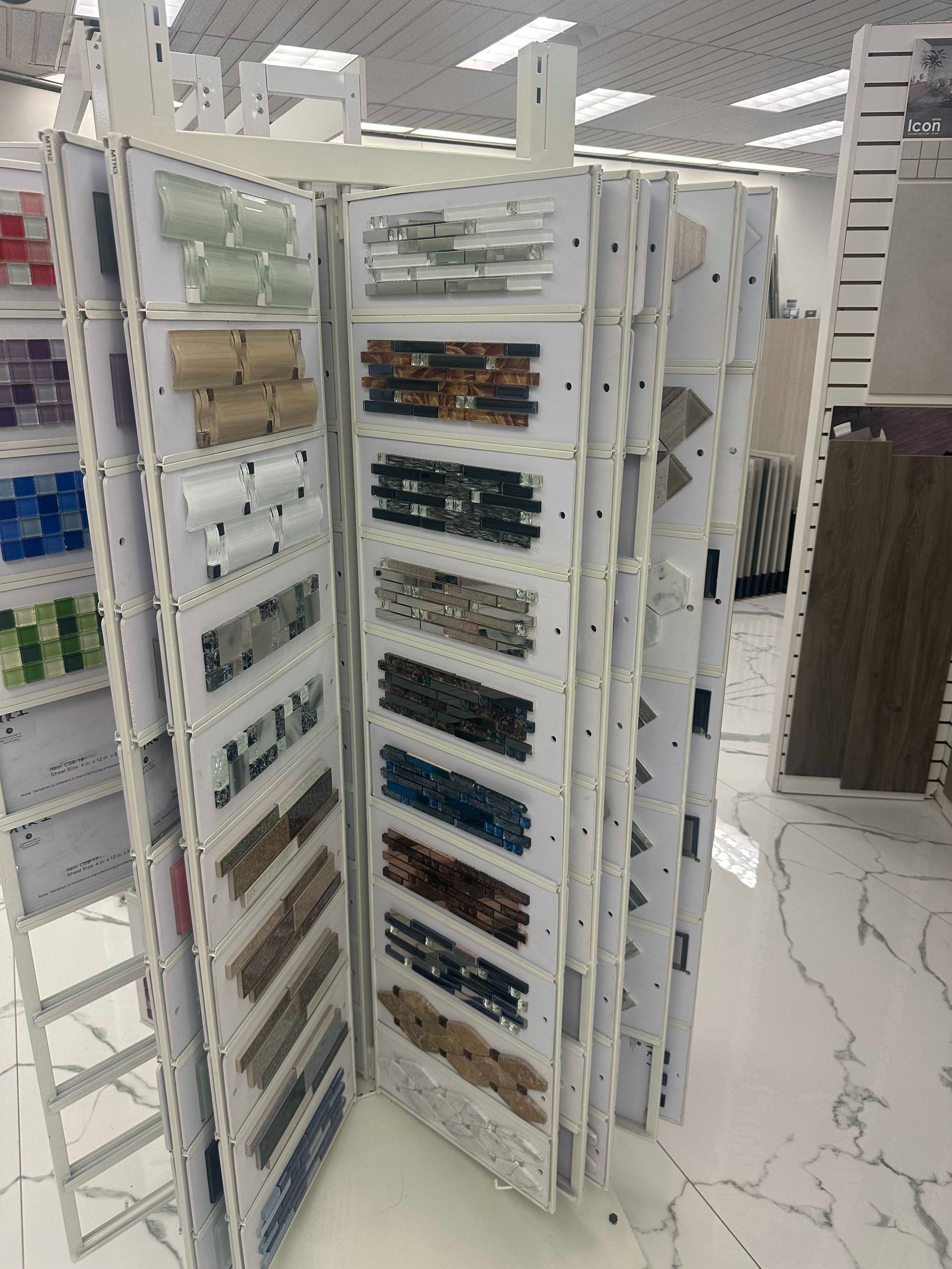 Display of tile samples on a rotating rack, various colors and textures, in a store.