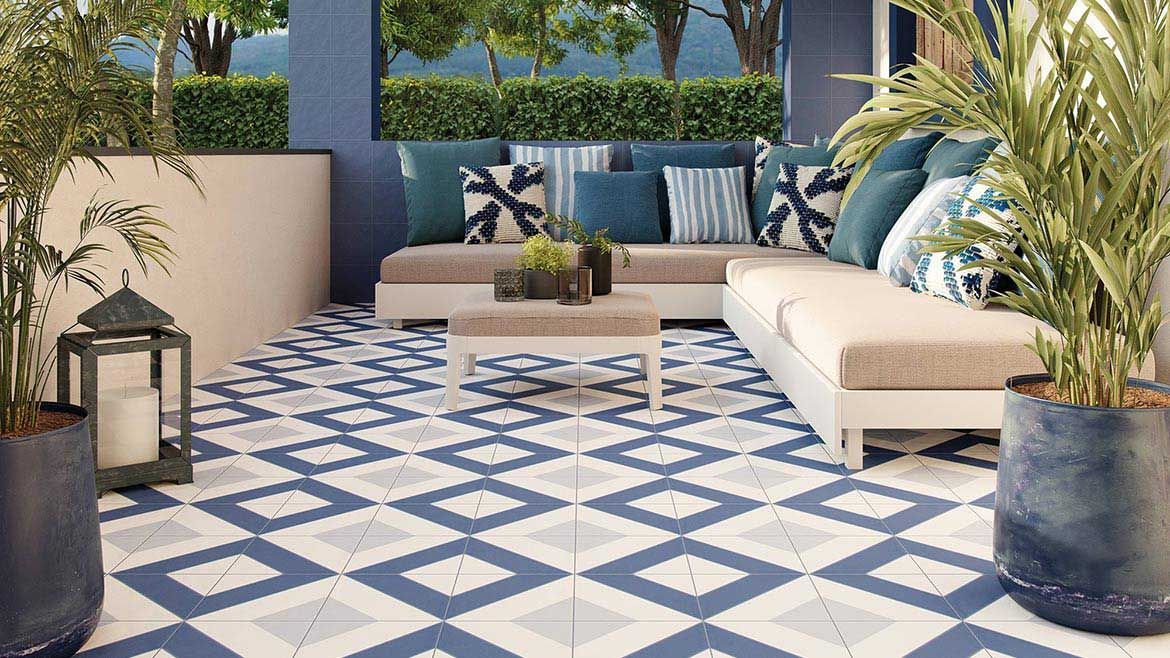 Outdoor patio with blue and white patterned tile flooring, seating, plants, and decorative pillows.