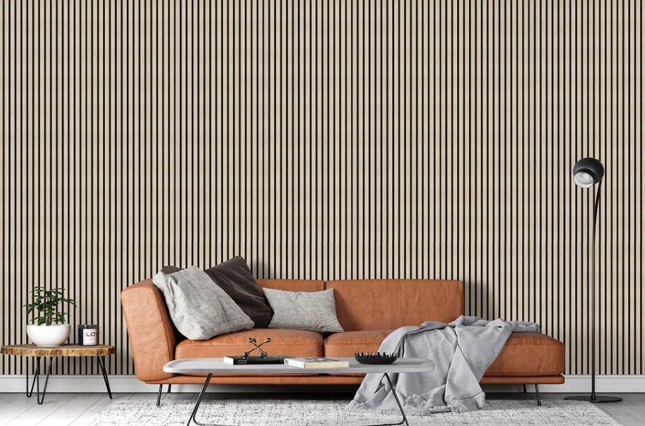 Brown leather sofa in front of a vertical wood-slat wall. A small table, floor lamp, and rug are in the room.