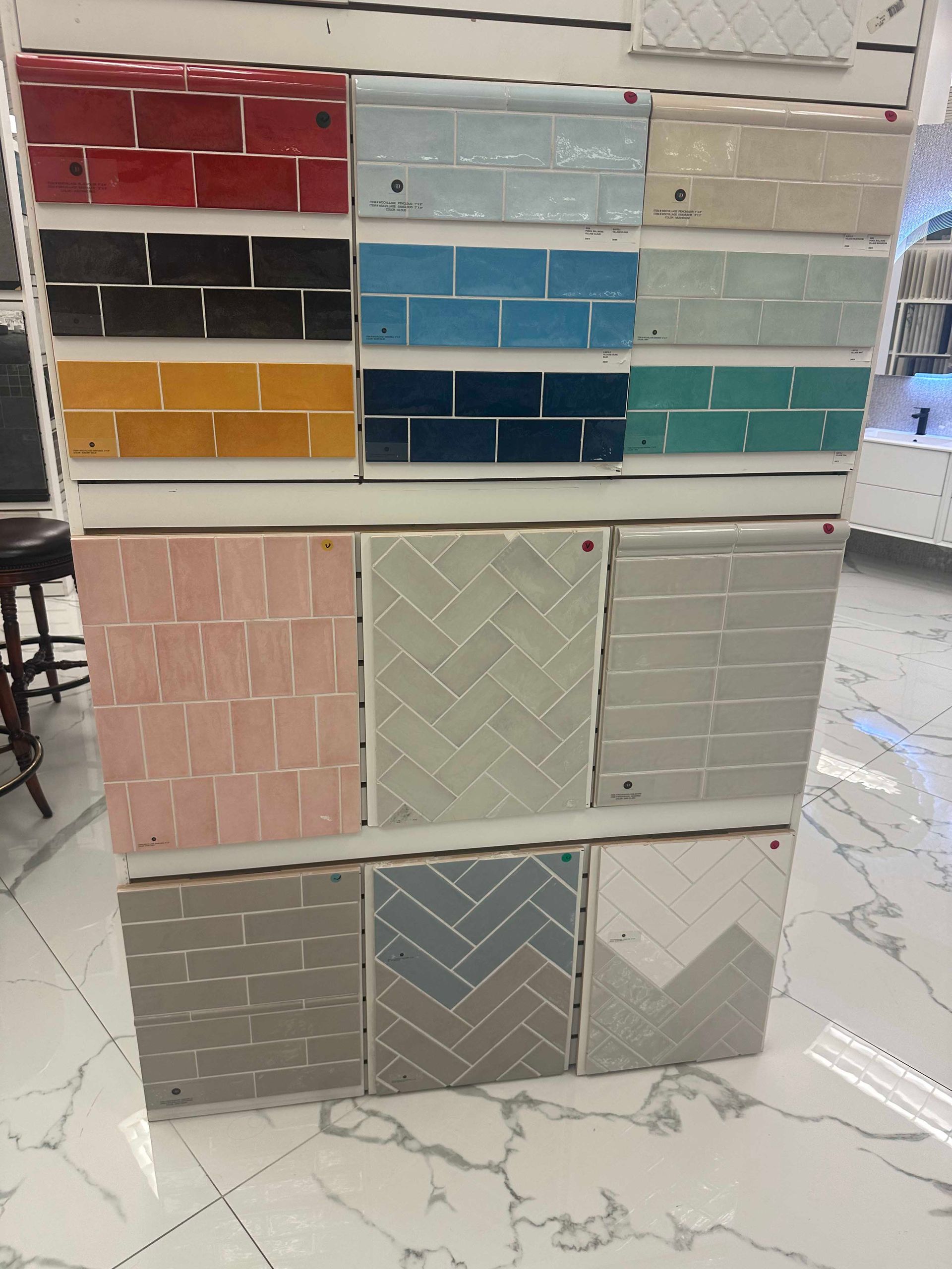 Tile samples in various colors and patterns displayed on a showroom wall.