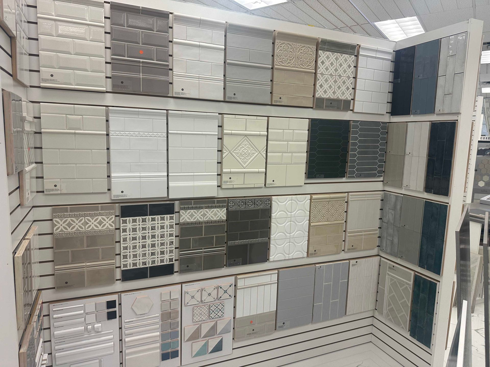Tile samples displayed on a wall in a store, various colors and textures.