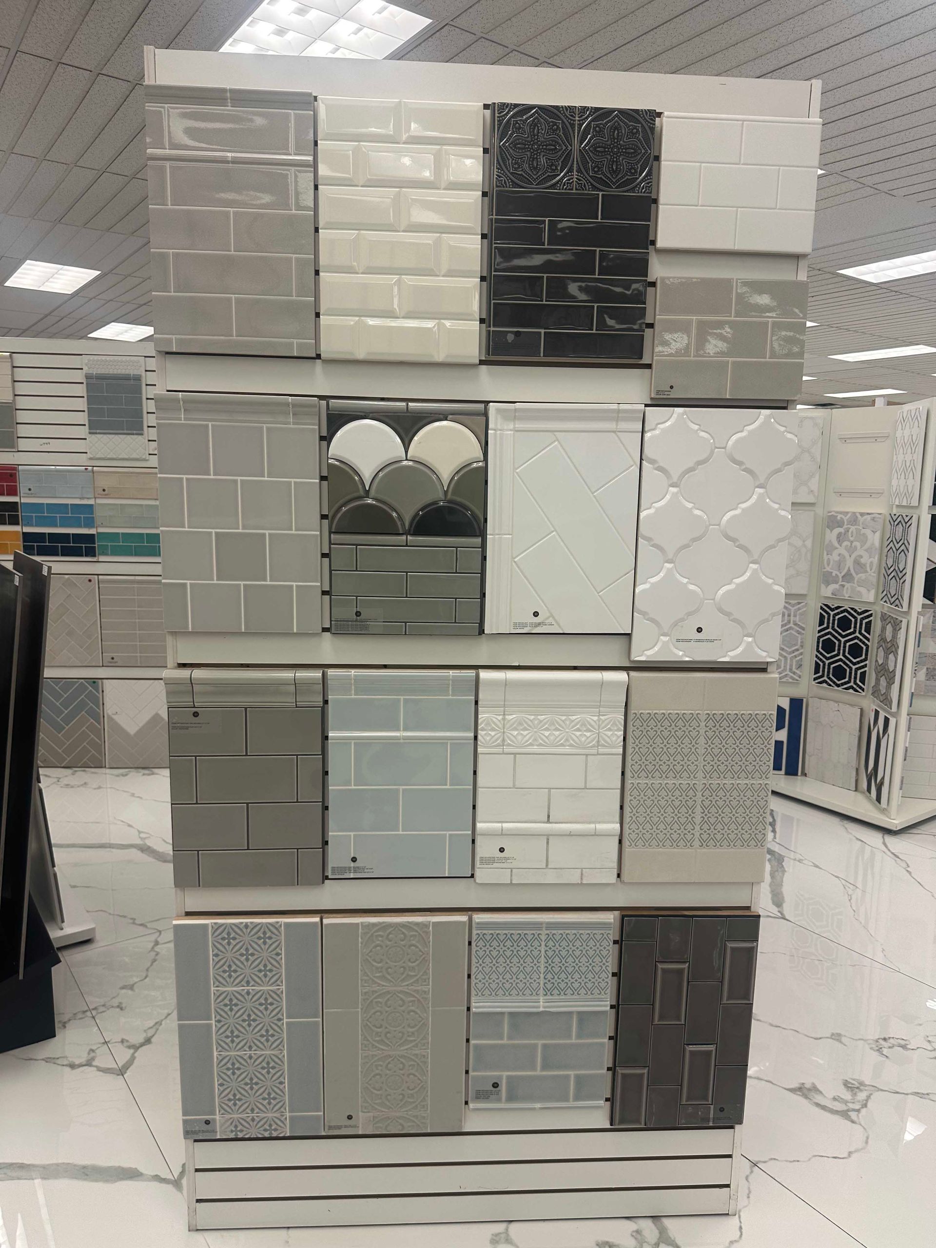 Tile samples displayed on a rack in a showroom, various textures and colors.
