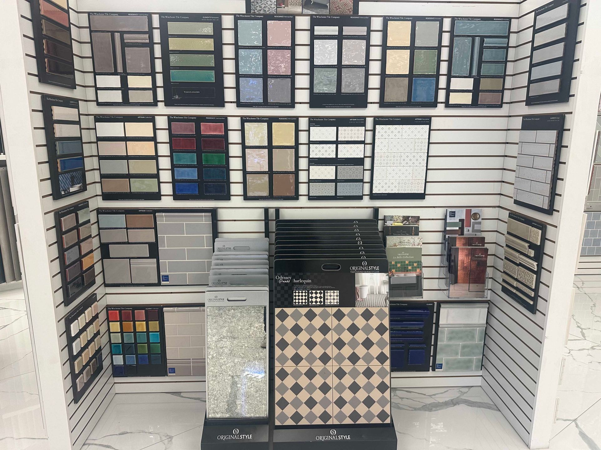 Tile samples arranged on a display in a store; various colors and patterns.