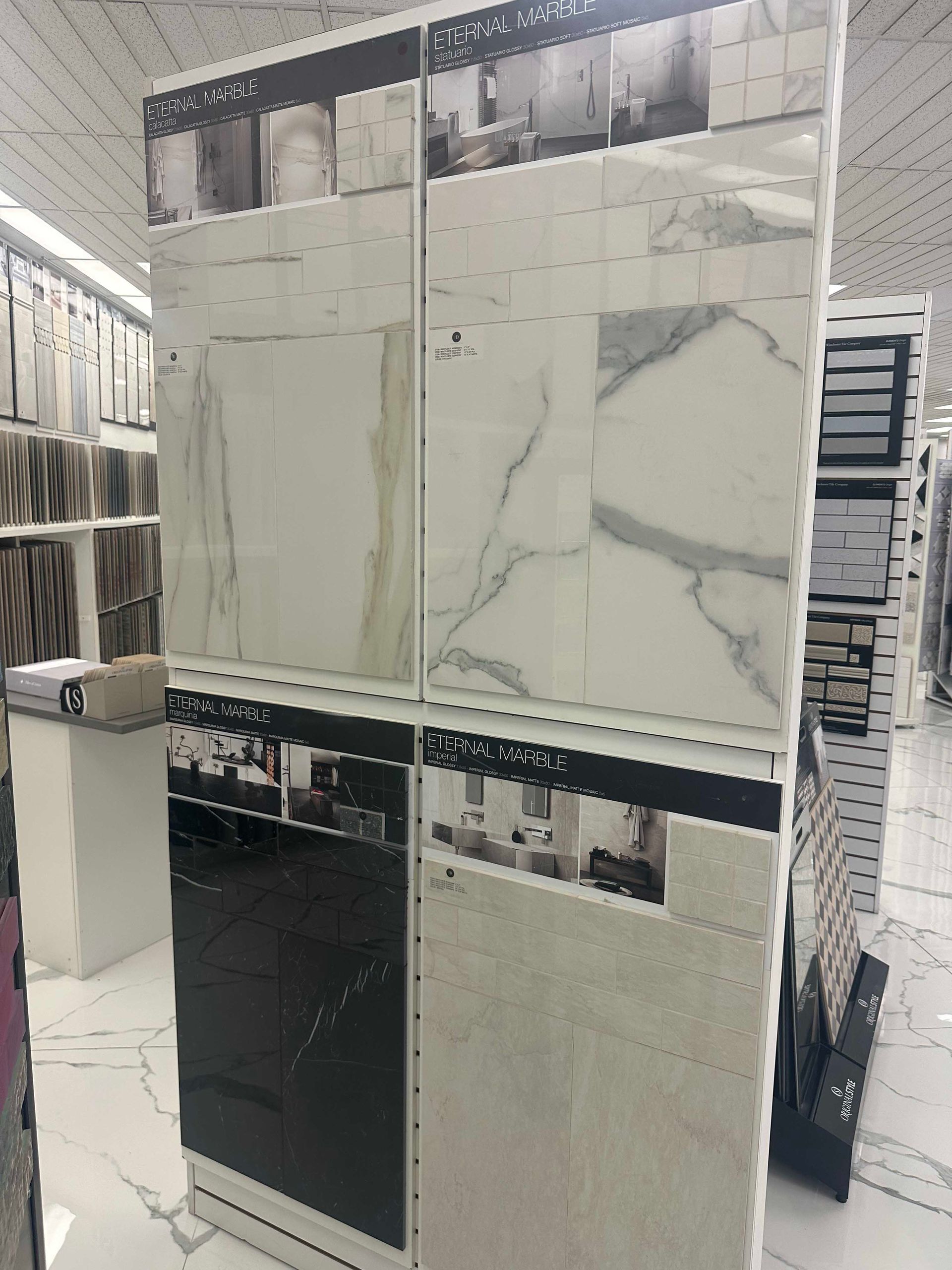 Tile display stand in a store, showcasing various ceramic tile patterns in white and black.