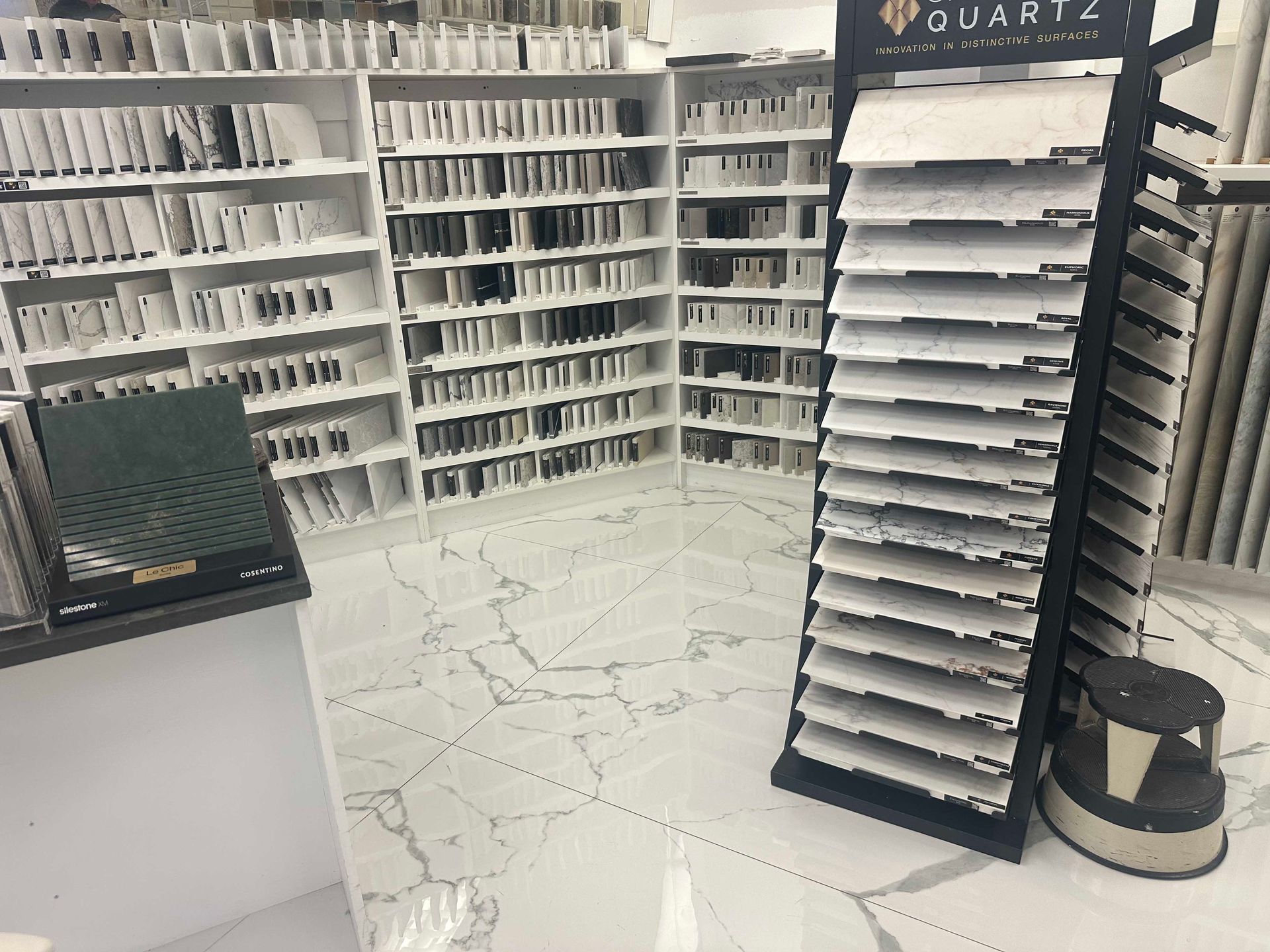 Stone tile samples on display in a showroom, arranged on shelves and a rotating stand.