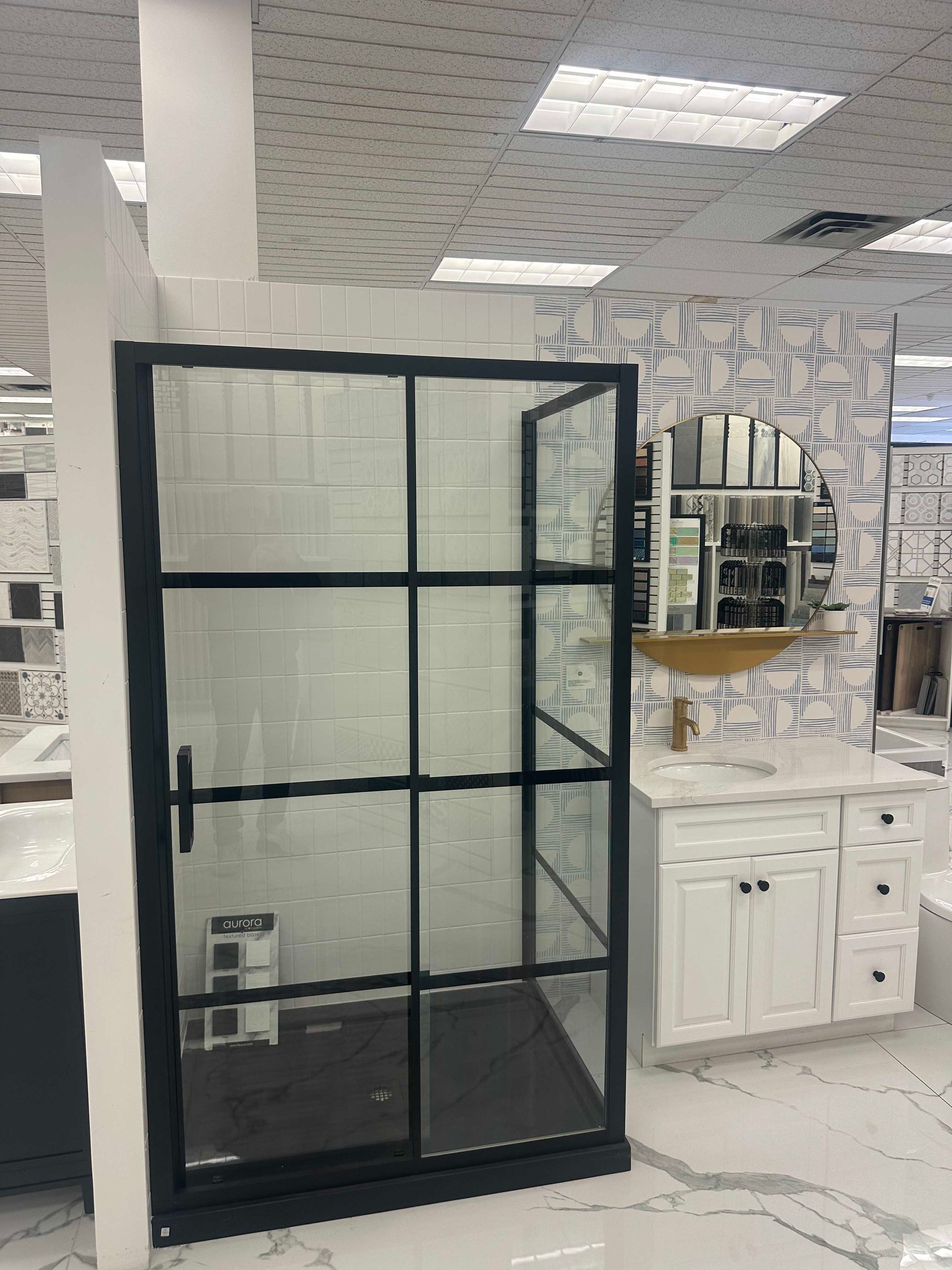 Black-framed shower enclosure with white tiled walls in a bathroom display. Vanity and mirror visible.
