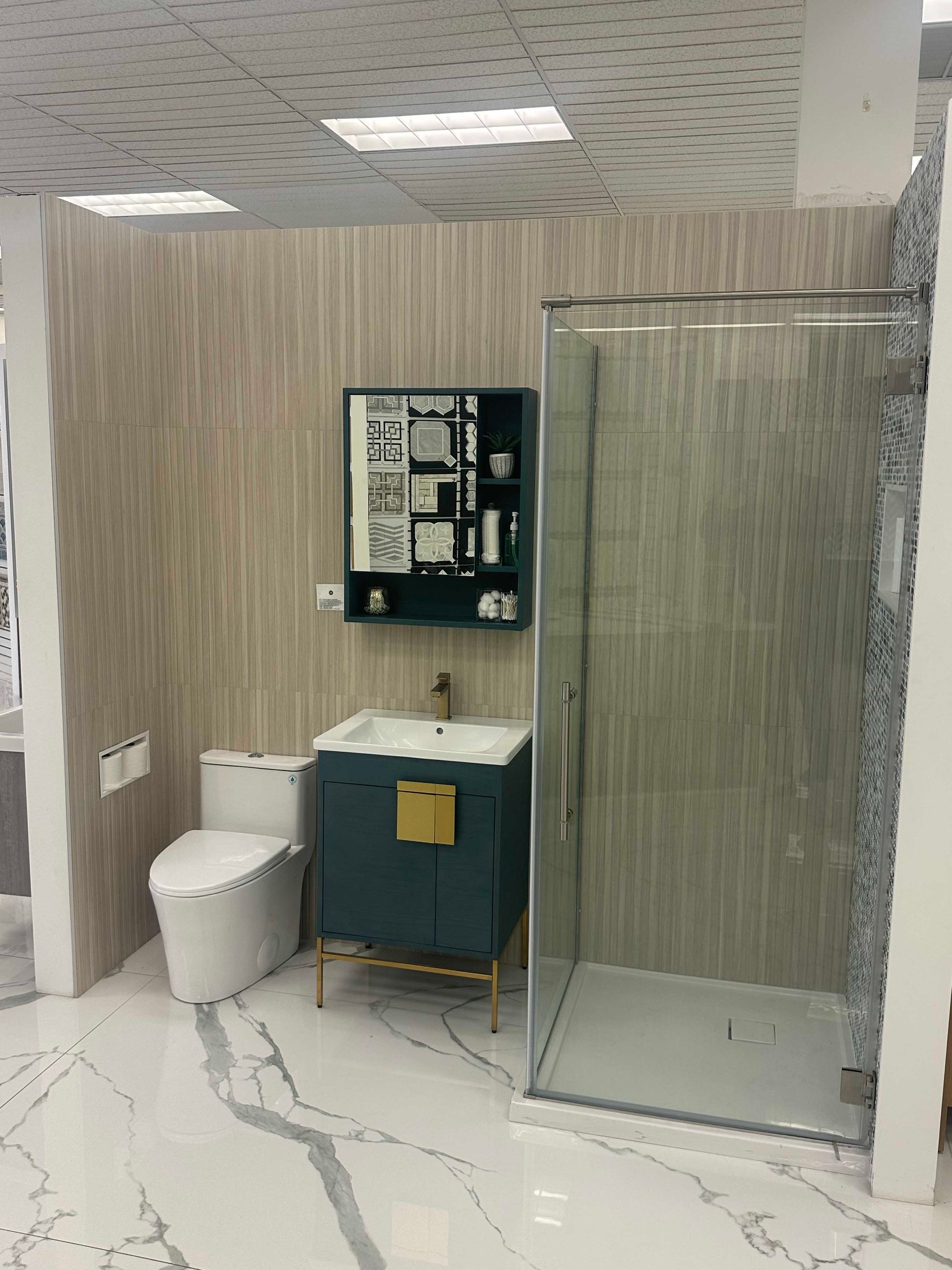 Bathroom display with toilet, vanity, shower, and mirrored cabinet against textured wall.
