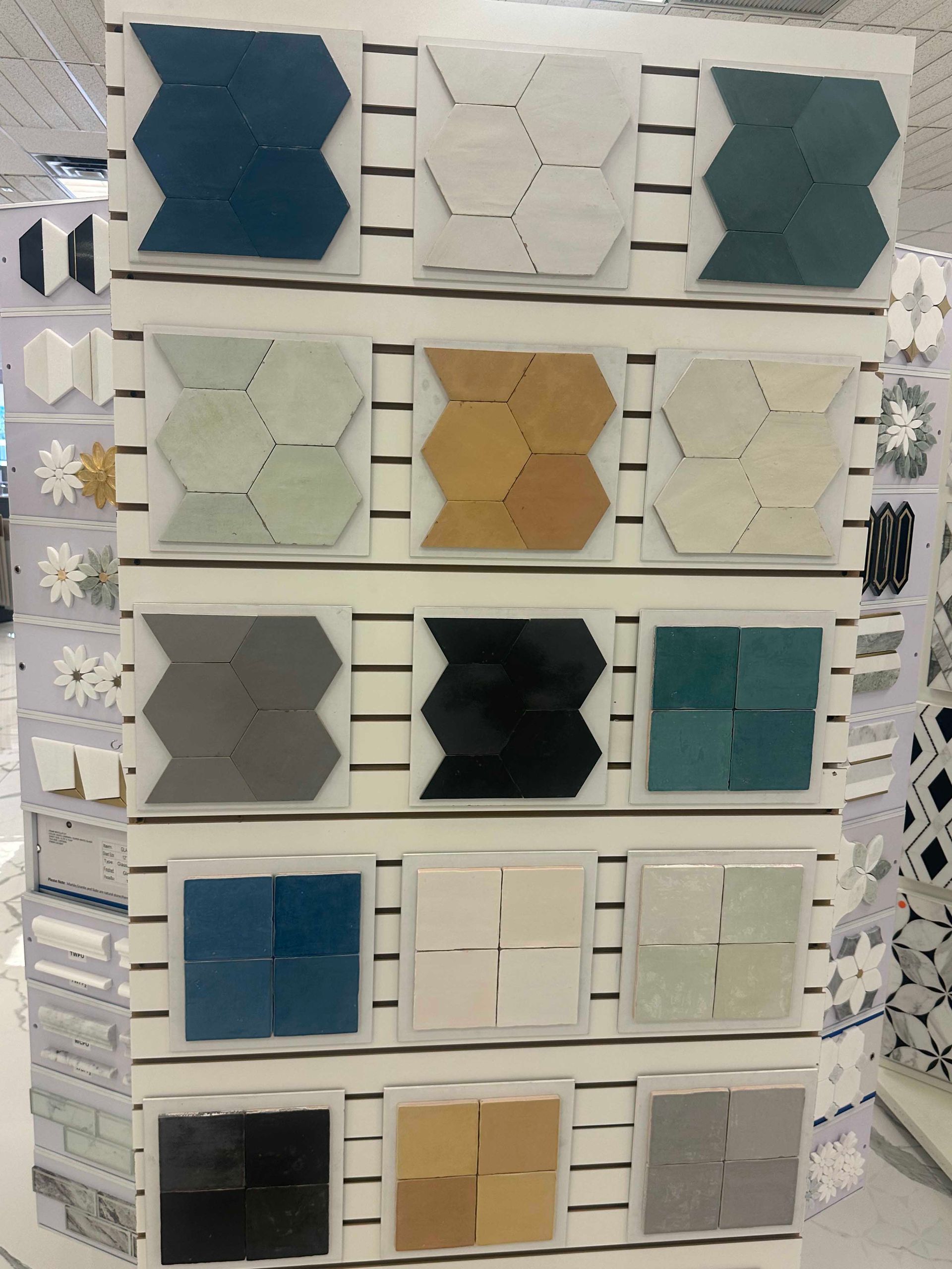 Tile samples on display, various colors and geometric shapes, arranged on a store display.